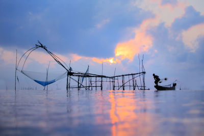 Silhouette fishing boats in sea against sky during sunset