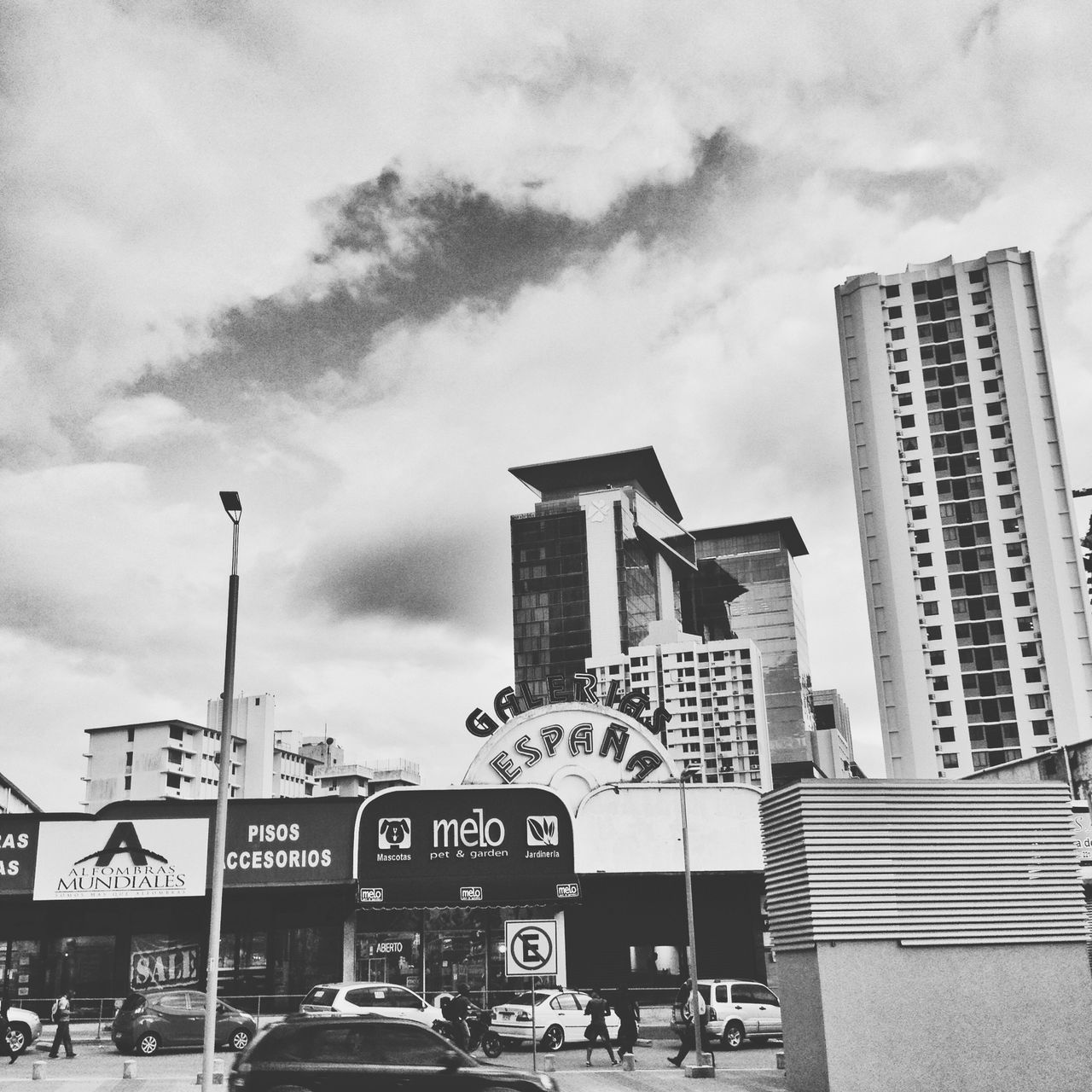 building exterior, architecture, built structure, sky, cloud - sky, street, city, land vehicle, transportation, low angle view, car, street light, road, cloudy, road sign, city life, incidental people, cloud, day