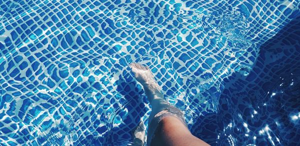 Low section of man swimming in pool