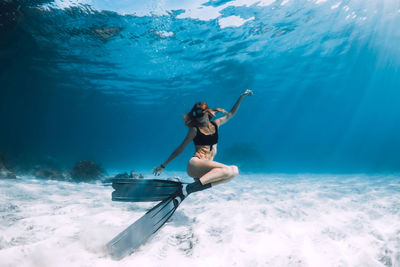 Rear view of woman swimming in sea against sky