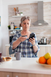 Woman doing online shopping through smart phone at home