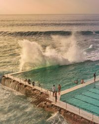 High angle view of waves splashing on infinity pool during sunset