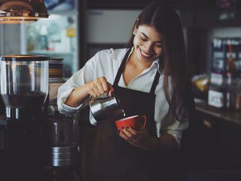 Smiling young woman pouring drink in cup