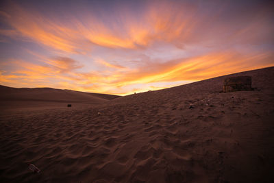 Empty plastic bottles on sand by water storage tank in desert