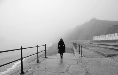 Rear view of woman walking on bridge in foggy weather