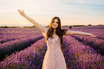 Portrait of woman with arms outstretched standing on lavender field