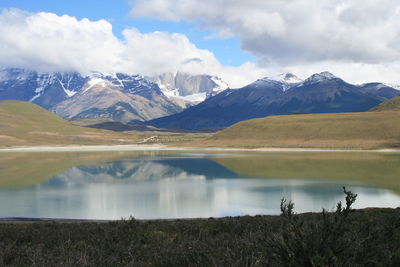 Scenic view of mountains and lake against cloudy sky