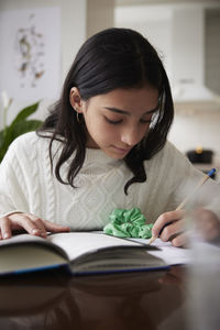 Girl doing homework at dining table