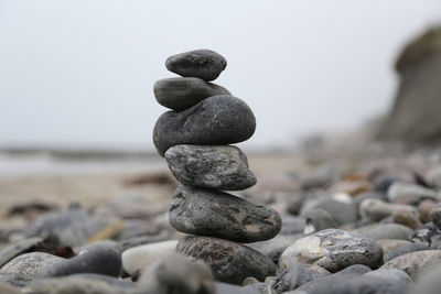 Stack of stones at beach against clear sky