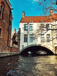 Bridge over river in city against sky