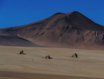 Scenic view of desert against clear blue sky