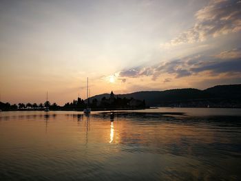 Silhouette sailboats in lake against sky during sunset