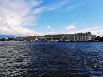 Scenic view of river by cityscape against sky