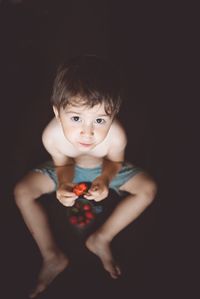 Portrait of cute boy standing against black background