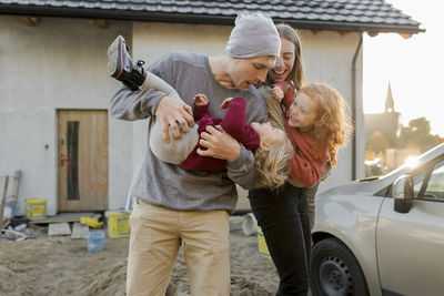 Daughters enjoying with parents outside house