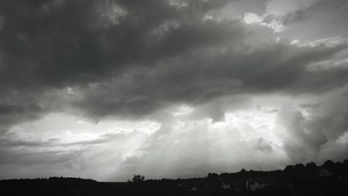 Low angle view of storm clouds over silhouette landscape