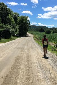 Rear view of woman on road against sky