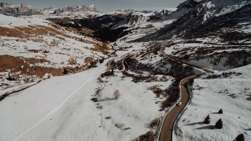 Snow covered road by mountains against sky