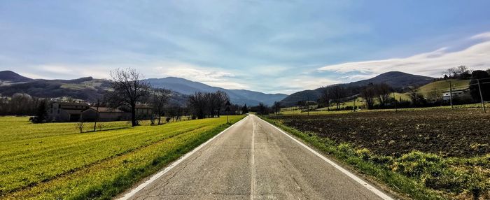 Road leading towards mountains against sky