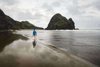 Rear view of man on beach against sky