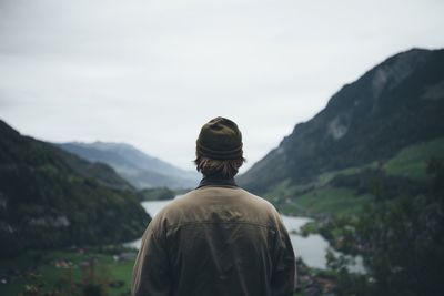 Rear view of man standing on mountain against sky