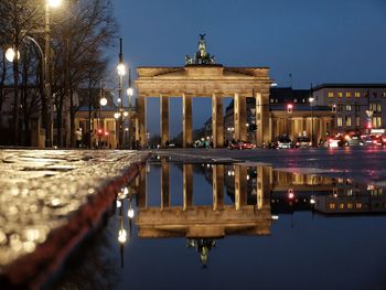 Reflection of building in puddle at night