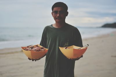 Portrait of mid adult man standing against sea