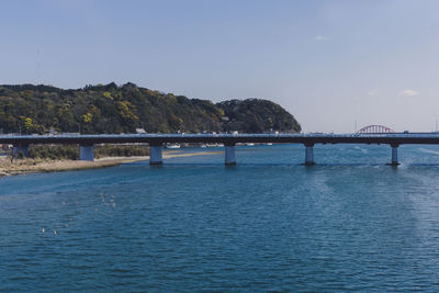 Bridge over sea against clear blue sky