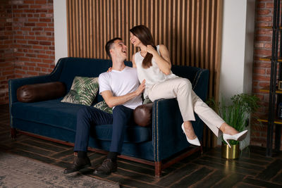 Happy young caucasian couple real estate buyers rejoice sitting on couch