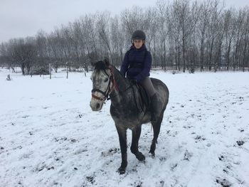 Teenage girl riding horse on snow covered field