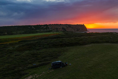 Car on field against sky during sunset