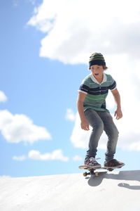 Teenager skateboarding on skateboard against sky