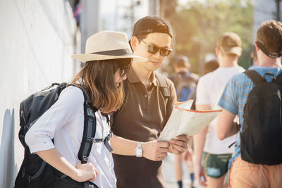 Man standing with woman holding map outdoors