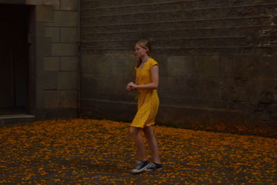 Full length of woman standing against yellow wall