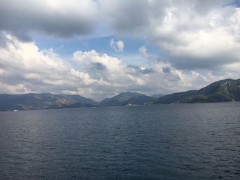 Scenic view of sea by mountains against sky