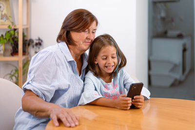 Friends using mobile phone while sitting at home