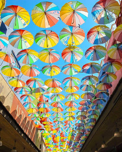 Low angle view of multi colored umbrellas hanging on building