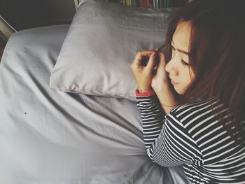 High angle view of thoughtful woman lying on bed