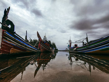 Fishing boats moored in lake against sky