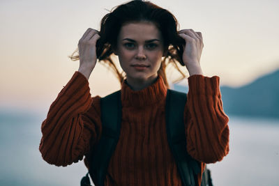 Portrait of young woman standing against sky