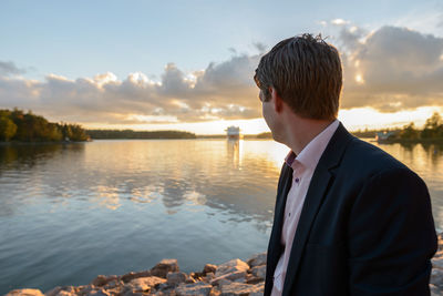 Man looking at lake against sky during sunset