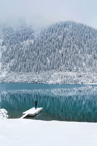 A man stands on the boat pier of a mountain lake in winter. winter landscape.