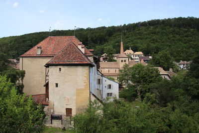 Houses by trees and buildings against sky
