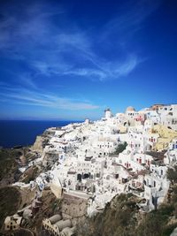 Aerial view of town by sea against blue sky