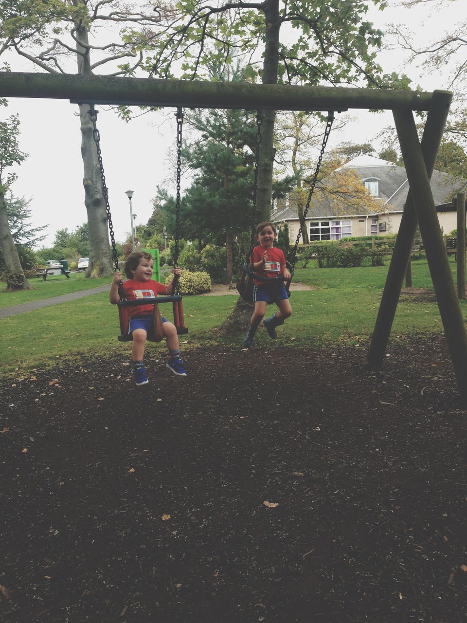 tree, grass, lifestyles, leisure activity, childhood, park - man made space, playground, field, full length, park, day, lawn, swing, playing, men, casual clothing, grassy, sitting