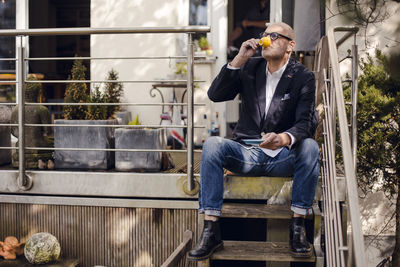 Senior man sitting on stairs of his patio, drinking coffee