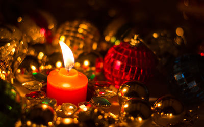 Close-up of lit candle amidst christmas decorations on table