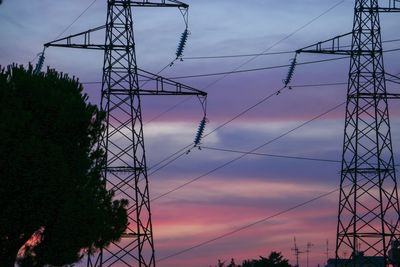 Low angle view of silhouette electricity pylon against sky at sunset