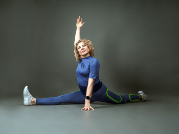 Side view of woman exercising against wall