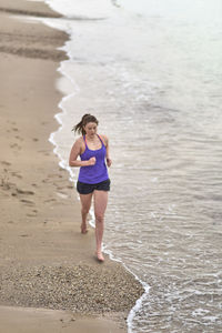 Full length of young woman running at beach